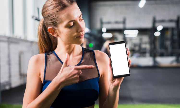 Donna che mostra lo smartphone per il indicare fitness digitale
