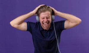 Giovane uomo con le cuffie stanco dei Tormentoni di Sanremo