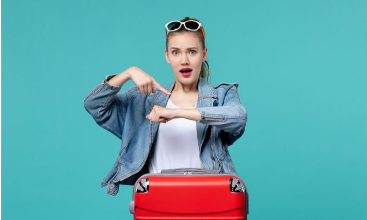 Donna con valigia e indice sul polso ad indicare Come organizzare un viaggio last minute